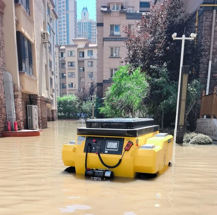 Remote-controlled drainage robot moving through muddy floodwater between residential buildings